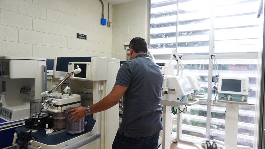 Technician checking a device in the equipment area, next to several ventilators