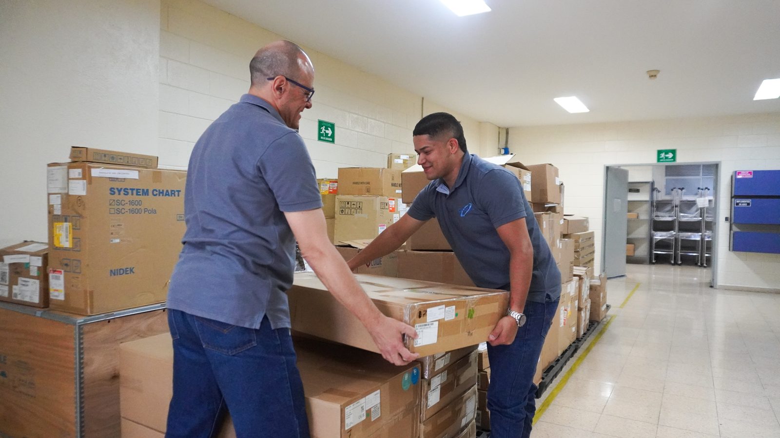 Dos personas del equipo de Quirurgil moviendo equipos en la bodega