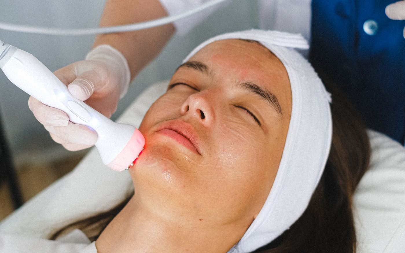 Profesional aplicando un equipo de estética sobre el rostro de una paciente